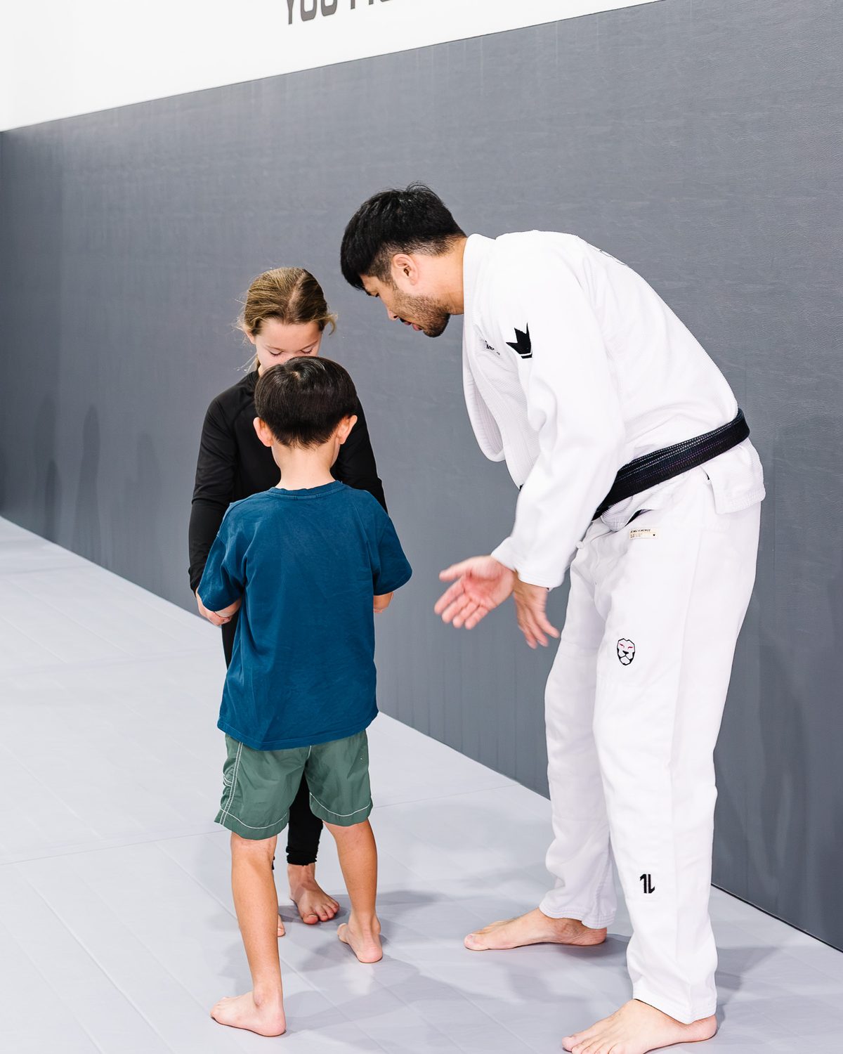 Coach Brian Yi working one-on-one with a young student while his parent looks on